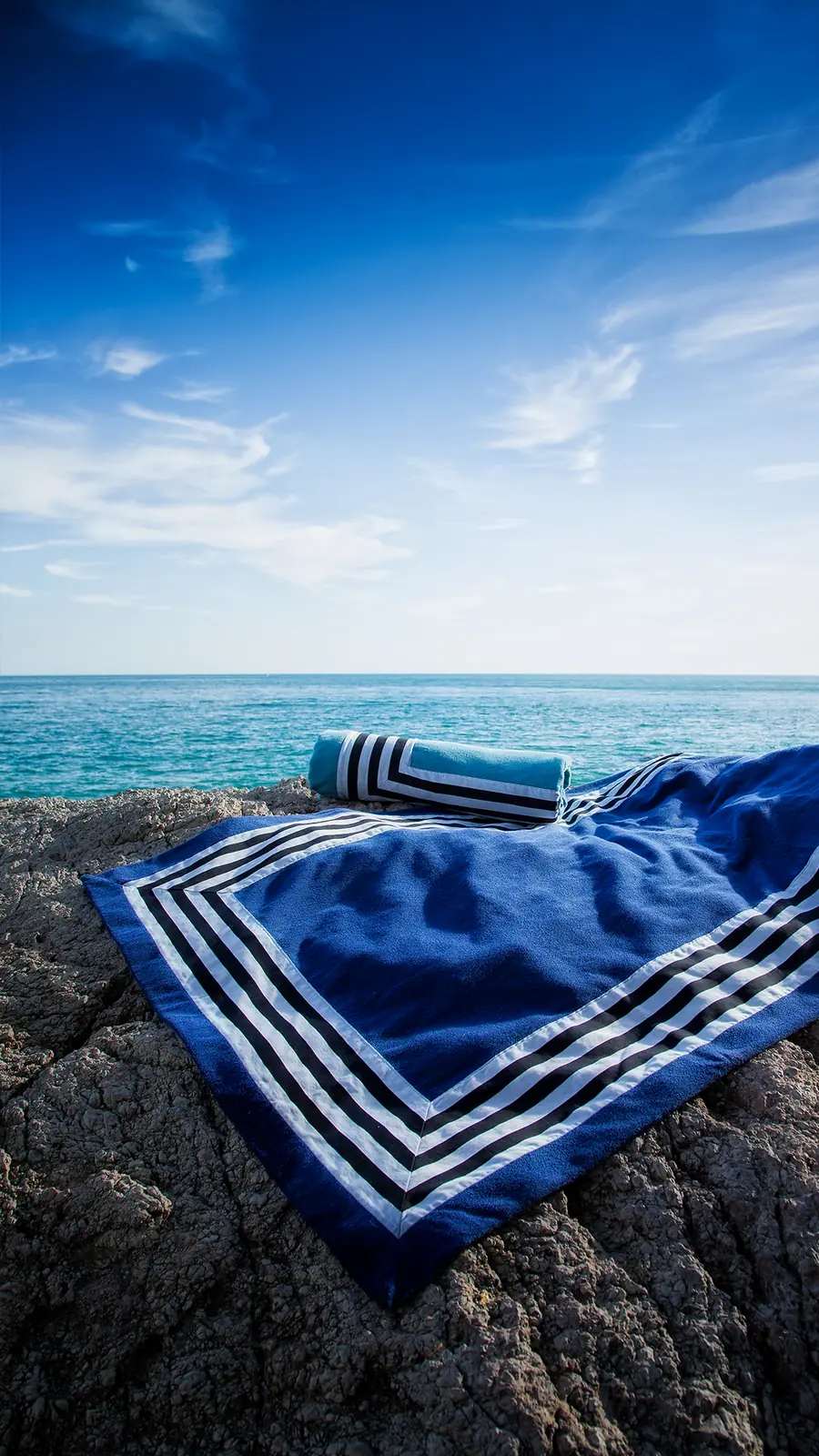 Blauwe strandlakens met witte strepen aan zee. Badtextiel van Abyss & Habidecor.