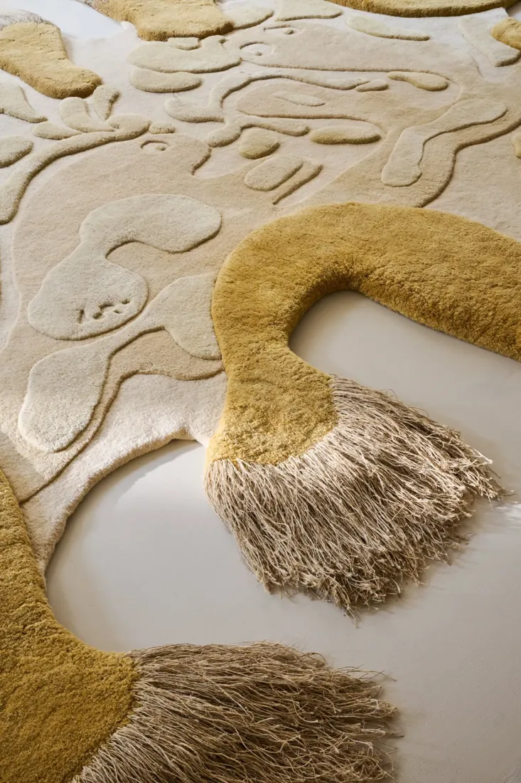 Detail van een tapijt met goudkleurige franjes en reliëf. Tapijt van Amini.