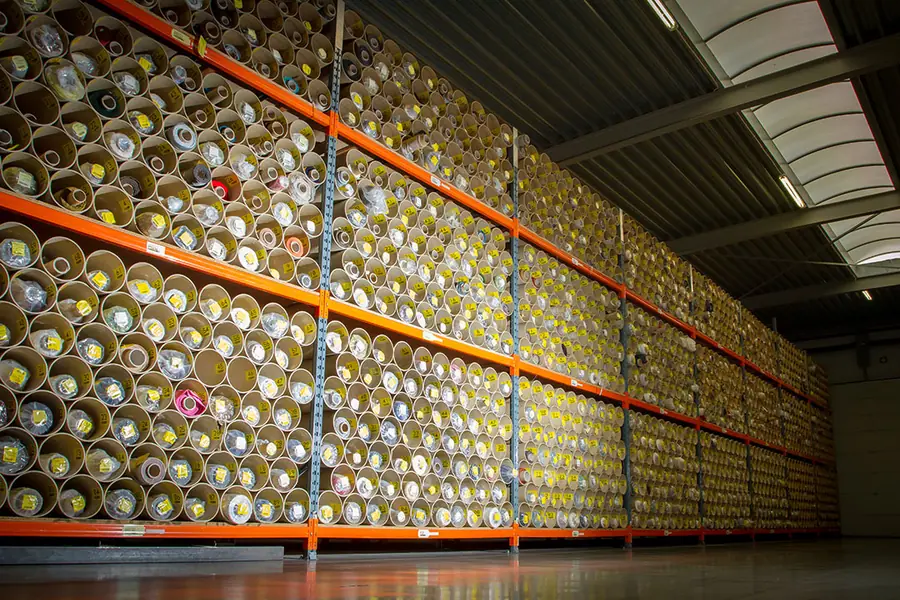 Magazijn met rollen stof op rekken. Stoffen van Artex.