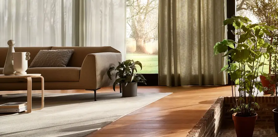Woonkamer met gordijnen en houten vloer. Stoffen van Artex.
