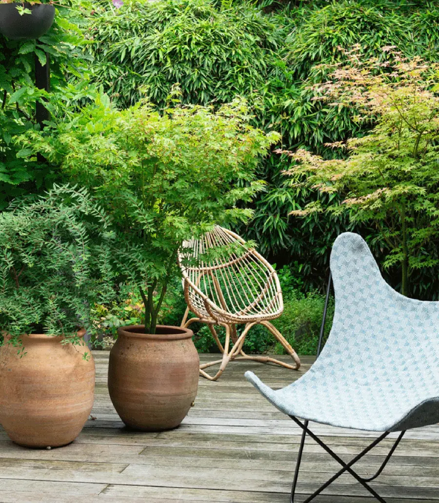 Terras met stoelen tussen het groen. Stoffen van Bruder.