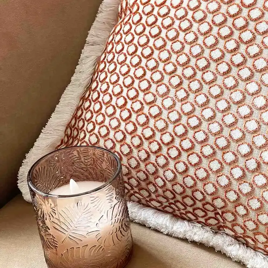 Terracotta kussen met kaars van dichtbij. Stoffen van Camengo.
