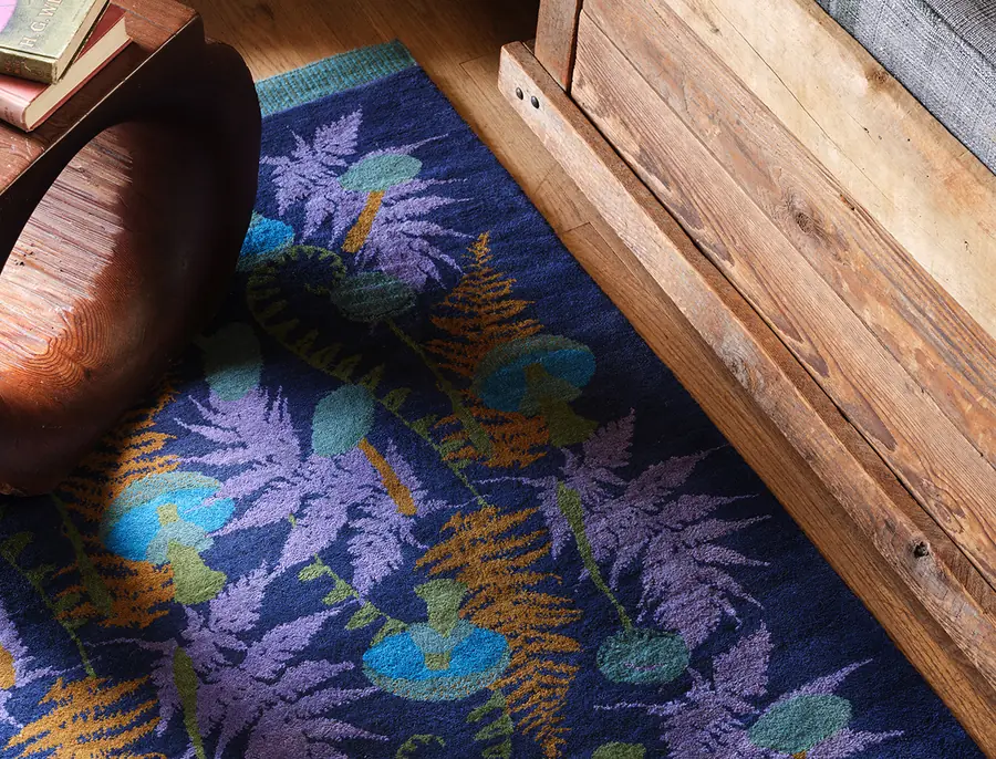 Blauw varentapijt bij een houten meubel. Stoffen van Christopher Farr.