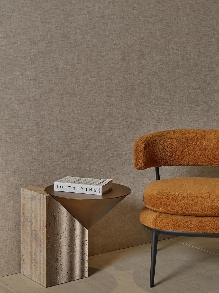 Okerkleurige fauteuil voor linnen wandbekleding. Behang van Dutch Wall Textile.