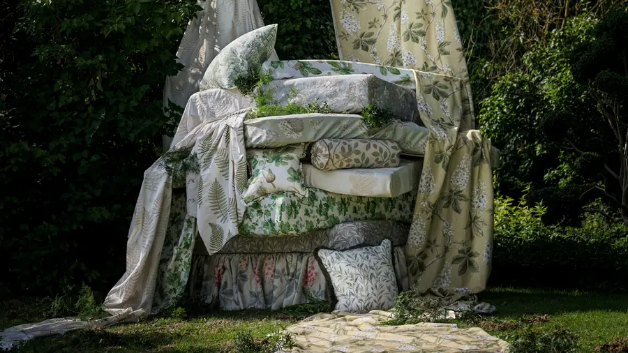 Gestapelde stoffen uit de Country Woodland-collectie van Sanderson in een tuin. Stoffen van Harvizo.