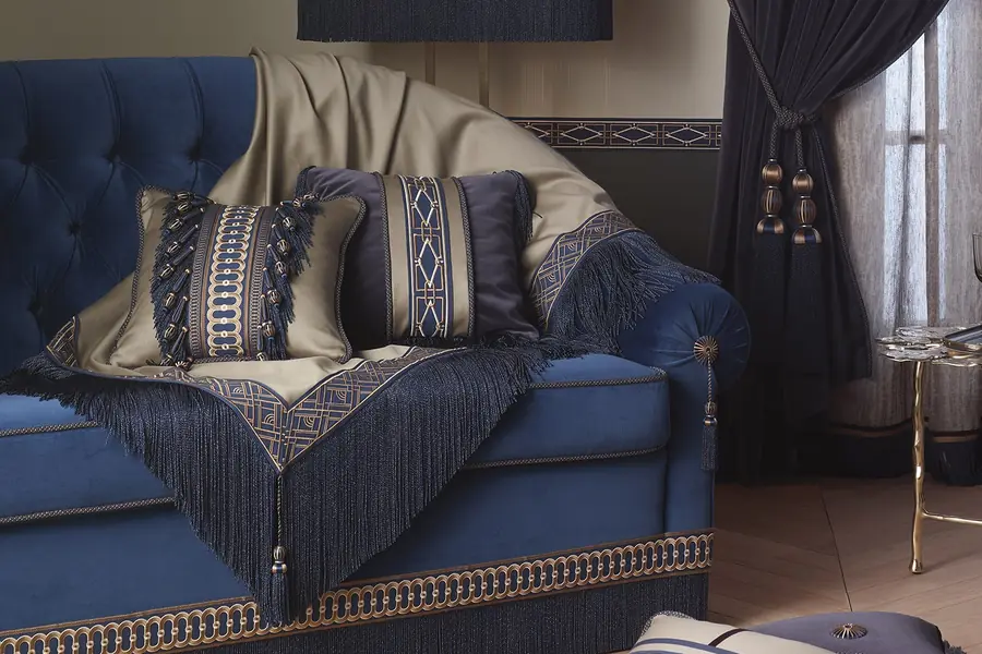 Blauwe sofa met gefranjerde kussens. Passementerie van Houlès.