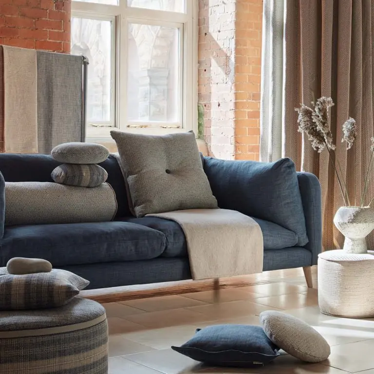 Blauwe sofa met gestreepte kussens in een loft. Stoffen van Ian Mankin.