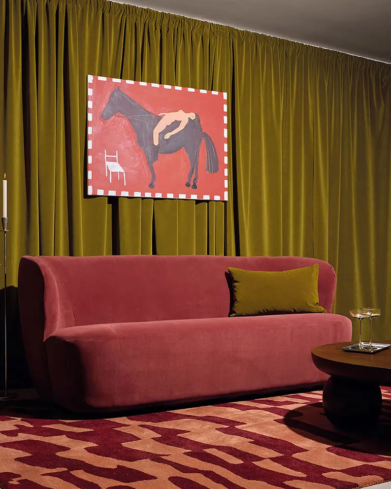 Bordeaux velours sofa op tapijt voor groen gordijn. Stoffen van Kirkby Design.