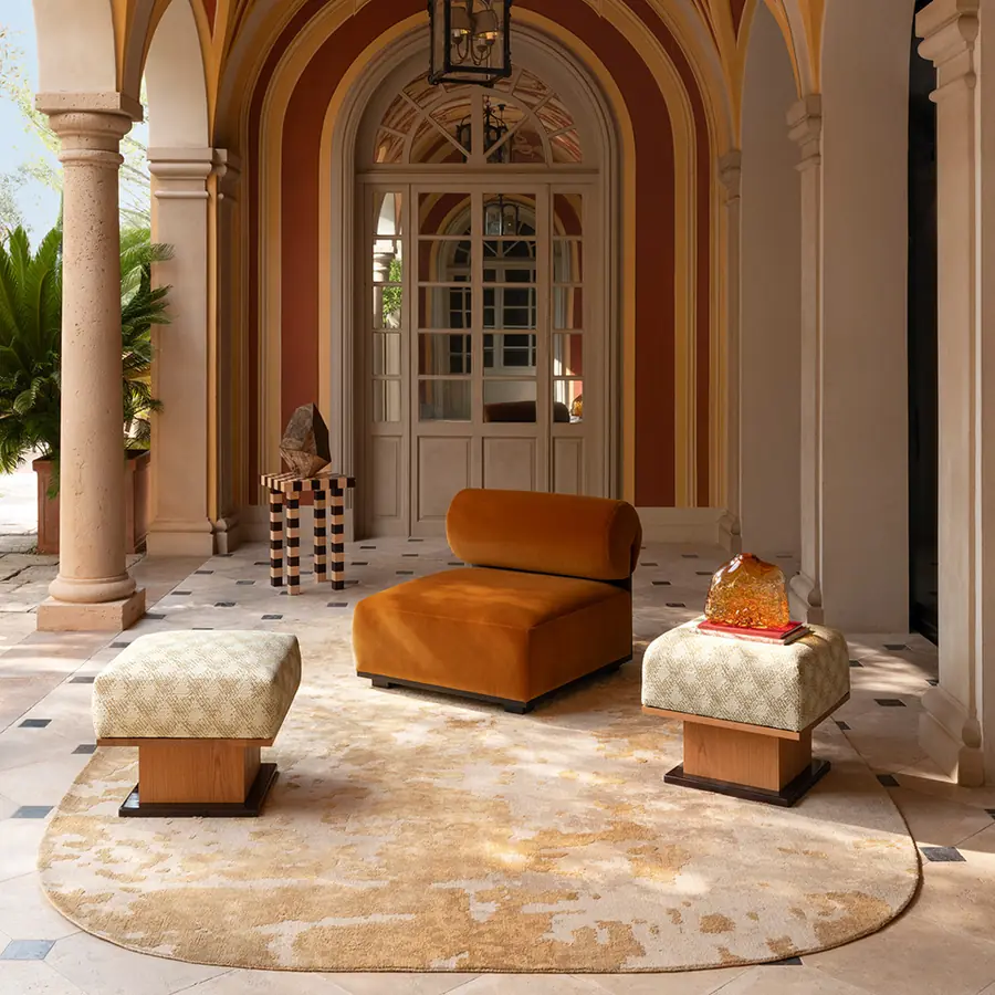 Oranje fauteuil en bedrukte poefen in een Italiaanse loggia. Stoffen van Misia.