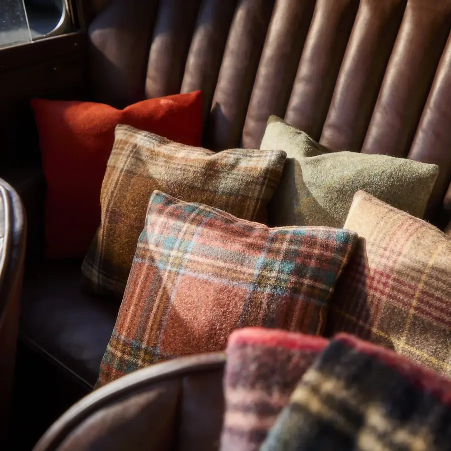 Geruite wollen kussens op een lederen chesterfield. Stoffen van Moon.