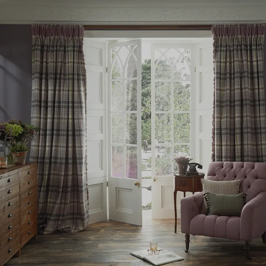Zitkamer met geruite wollen gordijnen en paarse fauteuil. Stoffen van Moon.
