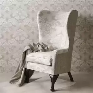 Beklede oorfauteuil voor damastbehang. Stoffen van Nina Campbell.