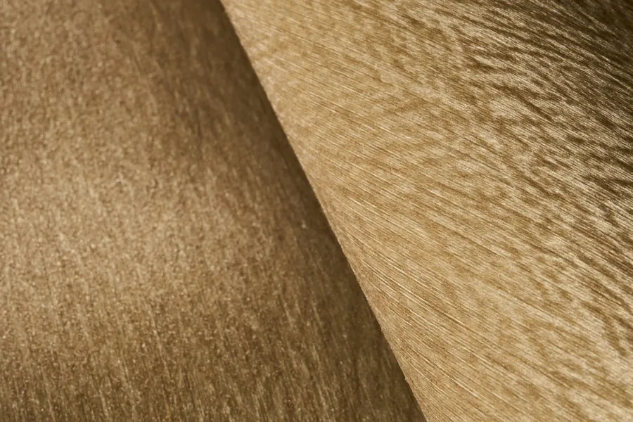 Goudkleurige wandbekleding met een geweven reliëf. Behang van Omexco.