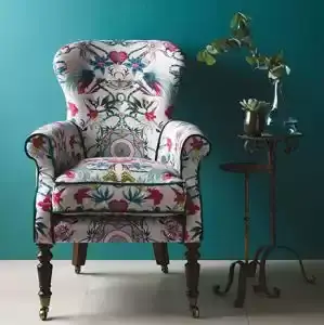Bloemenfauteuil voor een petrolblauwe wand. Stoffen van Osborne & Little.