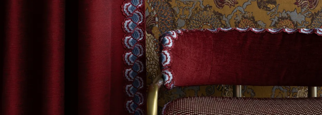 Rode bekleding met een geborduurde boord. Passementerie van Samuel & Sons.