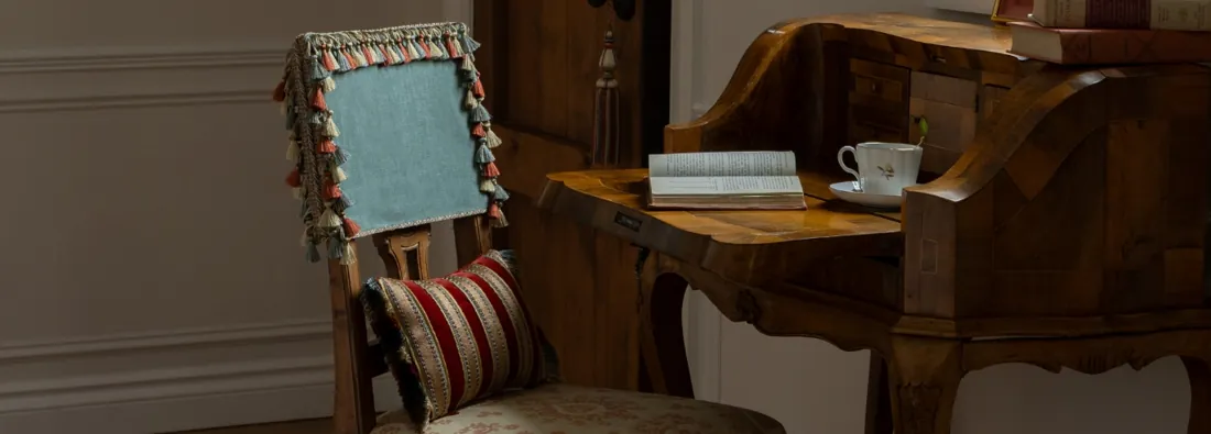 Stoel bij een bureau met afgeboorde bekleding. Passementerie van Samuel & Sons.