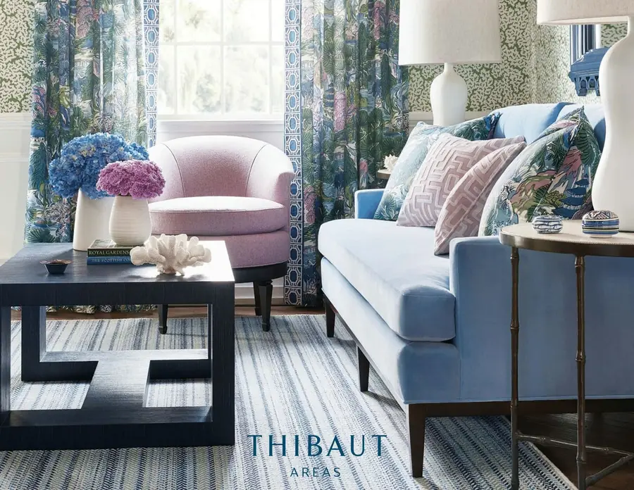 Salon met roze fauteuil en blauwe sofa. Behang van Thibaut.