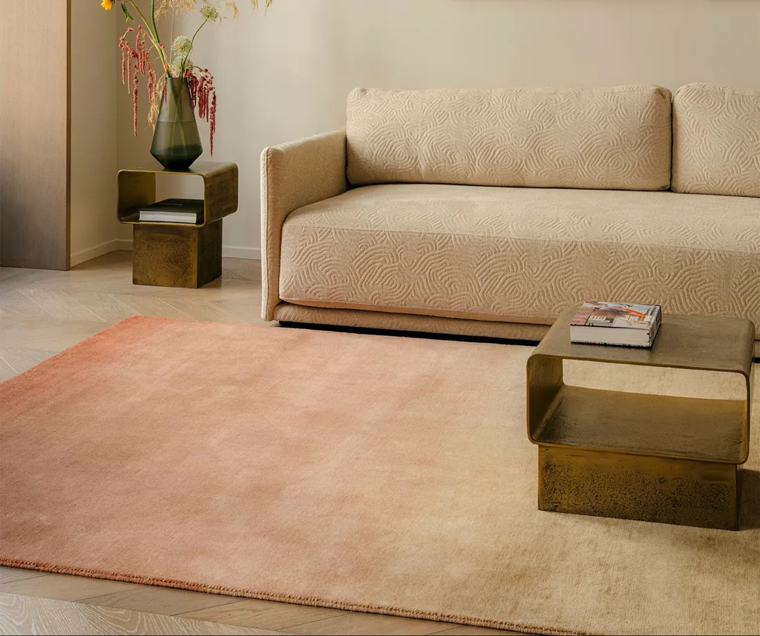 Roze tapijt onder een beige sofa. Tapijt van Toulemonde Bochart.