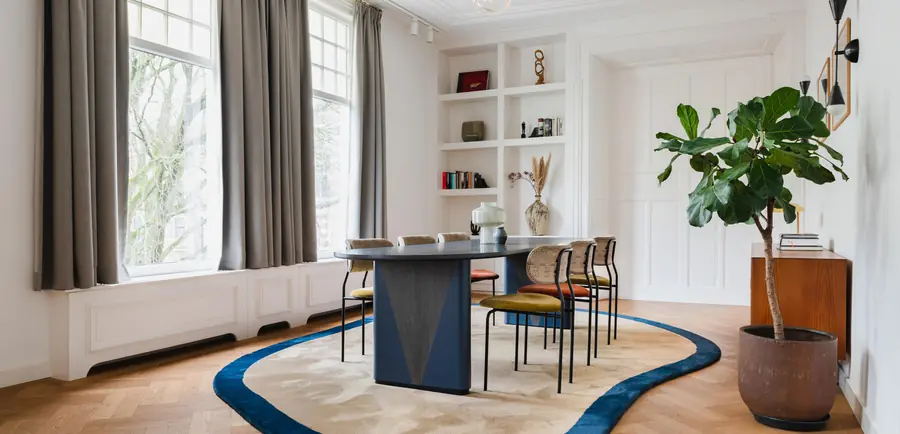 Eetkamer met licht tapijt met blauwe rand op parket. Tapijt van Van Besouw.