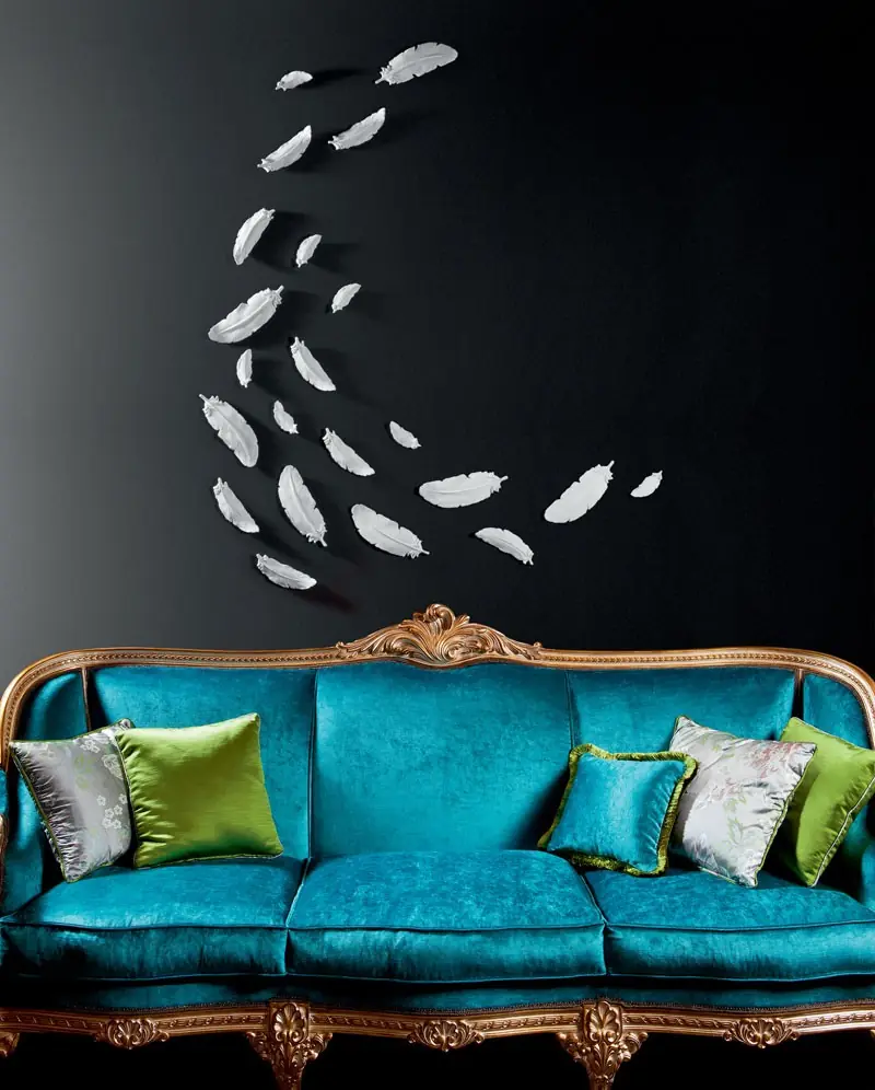 Turkooizen sofa tegen een donkere wand. Stoffen van Voghi.