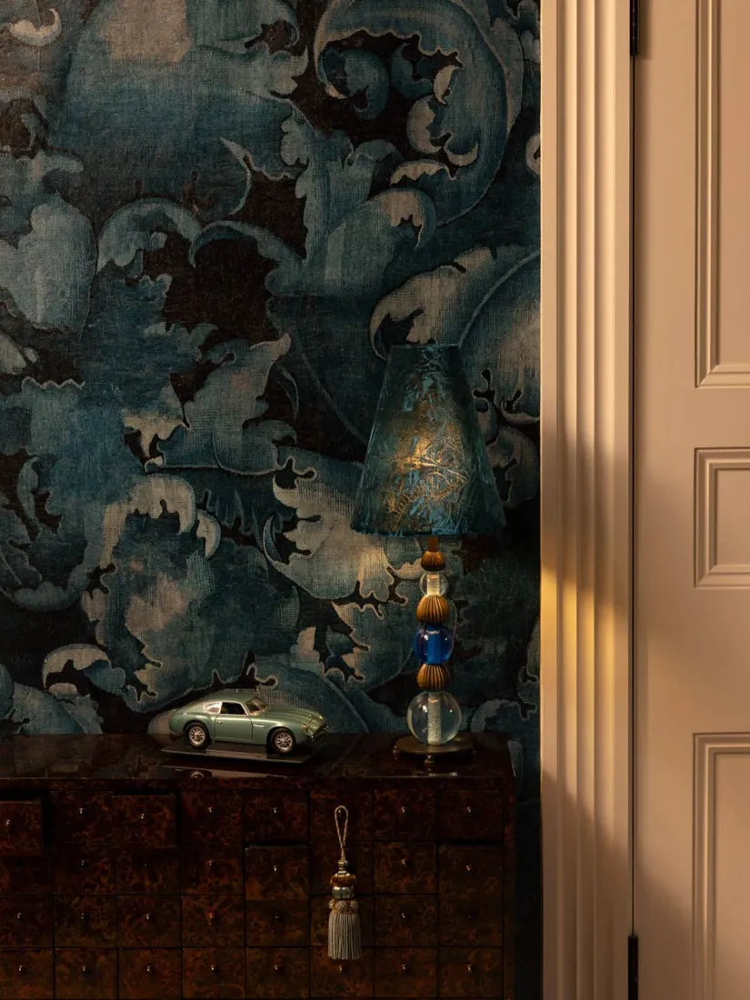 Wand met donker bladerbehang en een kast. Behang van Watts 1874.