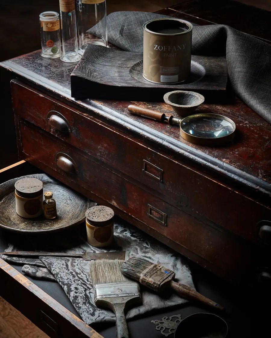 Verfpotten en penselen op de oude werkbank. Stoffen van Zoffany.