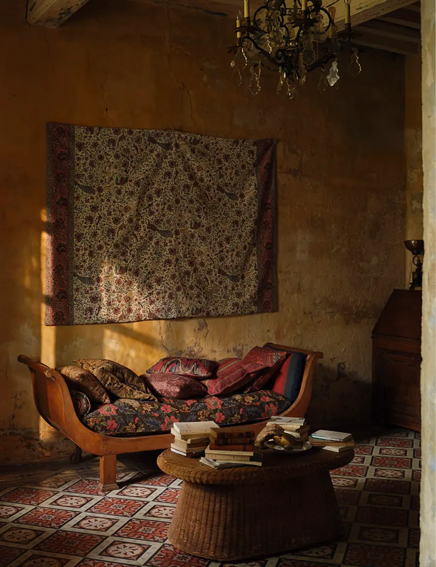 Warme kamer met wandkleed en gebloemde sofa. Stoffen van Zoffany.